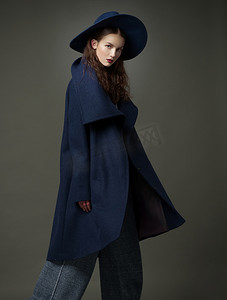 时尚模特女人外套和帽子城市风格造型在工作室中的颜色背景上