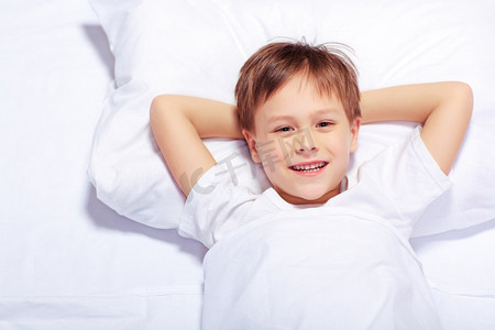 柔和度摄影照片_一个可爱的情感的小男孩躺在床上的肖像