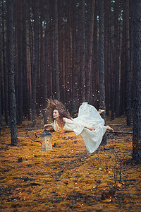 公主浪漫摄影照片_悬浮在她手里的手电筒在森林里的女人.
