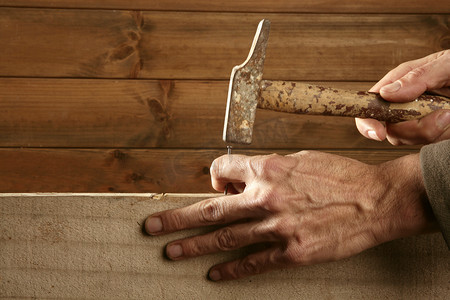 金色手指甲摄影照片_木匠与锤子木头的手和指甲