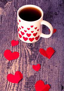 爱心咖啡摄影照片_情人节爱心和杯茶在旧木桌上。定了调子