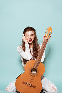 年轻漂亮的女孩微笑着与吉他合影