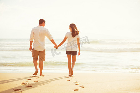 日落时分在海滩上散步的夫妻