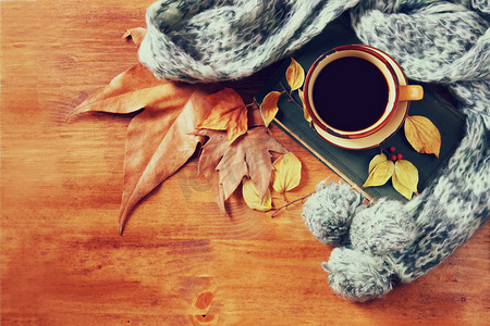 顶视图的杯黑咖啡与秋天的落叶、 暖和的围巾和木制背景上的老书。filreted 图像