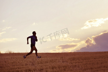 越野马拉松摄影照片_profile silhouette of young man running in countryside training in summer sunset