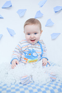 坐飞机的儿童摄影照片_微笑着可爱的小宝宝玩的白色绒毛的托儿所