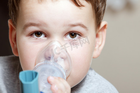 呼吸隔离摄影照片_男孩用治疗哮喘吸入器.