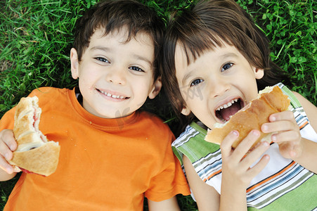 两个可爱的男孩铺设地面性质和快乐地吃健康的食物