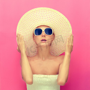 一个女孩在粉红色的背景上的一顶帽子的肖像