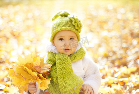 秋天黄叶中的秋天婴儿画像，毛帽中的小孩，公园户外的漂亮小孩，十月季节的针织服装
