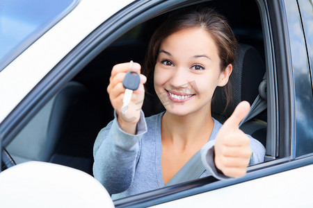 快乐的女孩，在一辆车，显示一个关键和拇指向上的手势