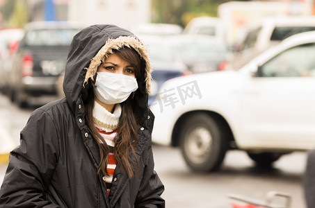年轻女孩步行穿上衣和掩码中污染的城市街道概念