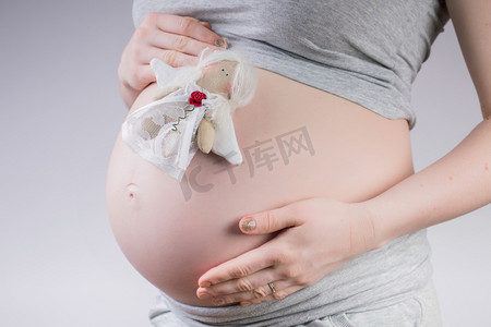 怀孕。孕妇控股肚皮上小玩具仙女