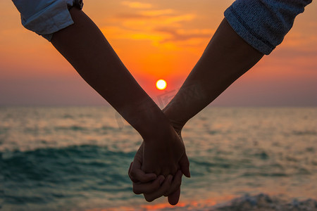 夫妇手牵着手在海上日落