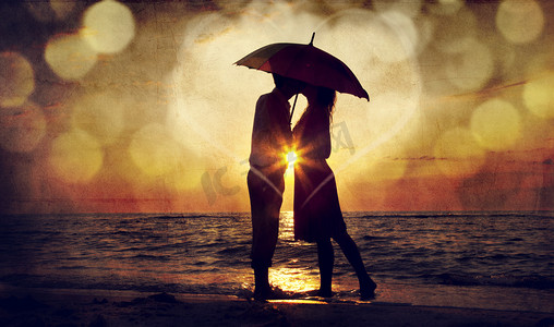 情侣亲吻袖套卡摄影照片_夫妇在日落在海滩伞下的亲吻。o 中的照片