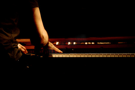 12舞台摄影照片_在钢琴演奏的男性钢琴家的温暖照片