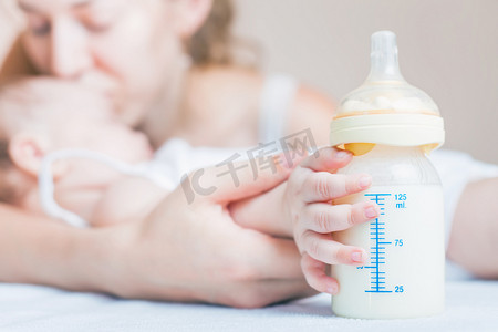 奶瓶瓶子摄影照片_Baby holding a baby bottle with breast milk