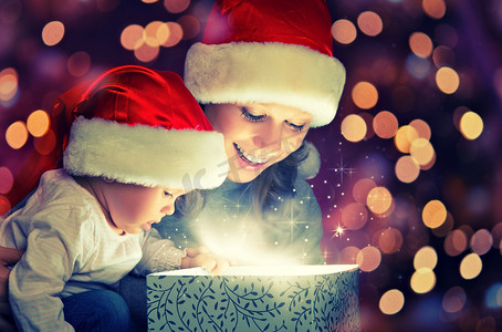 神奇的宝贝摄影照片_圣诞魔术礼品盒和快乐的家庭母亲和婴儿