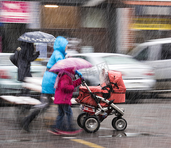 婴儿小推车摄影照片_在一个下雪天市街上的人们