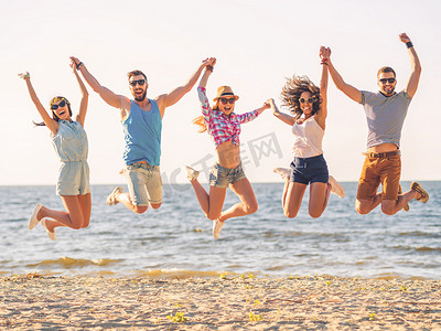 happy young people jumping on beach