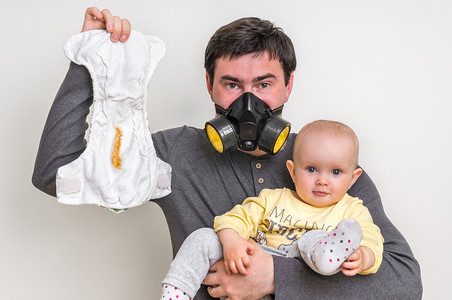 父亲带防毒面具抱着脏尿布和小宝宝