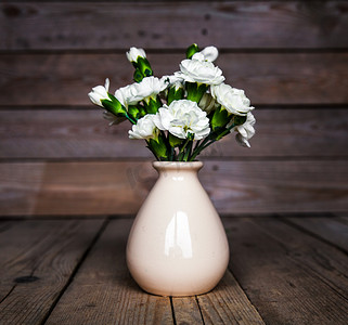 心脏蓝色背景摄影照片_精致束康乃馨古董花瓶及木制背景上心。情人节那天