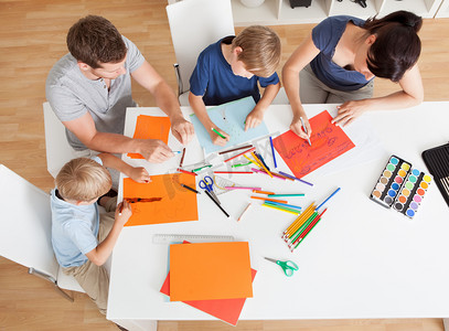 孩子彩色铅笔摄影照片_年轻的家庭，用彩色铅笔绘图