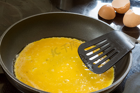 炒鸡摄影照片_在泛用于煎饼或炒鸡蛋蛋液