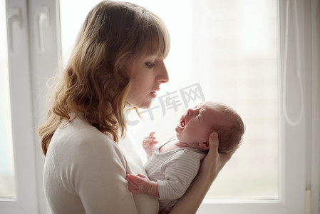 孩子和母亲摄影照片_年轻的母亲与婴儿哭