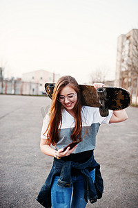 云彩涂鸦摄影照片_城市的年轻少女与滑板，戴上眼镜，帽子