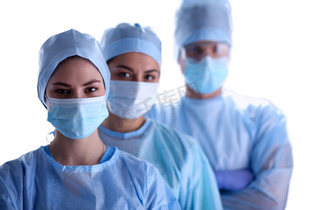 戴着防护服、帽子和面具的外科医生小组 