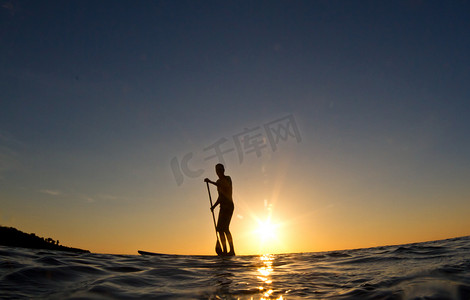 开心一家摄影照片_一个人在日落时划他的冲浪板的轮廓