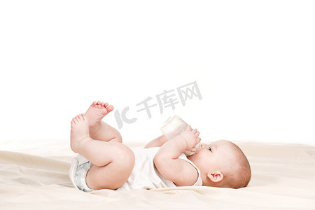 日系短发女摄影照片_可爱的婴儿，用一瓶牛奶在米色的毛毯