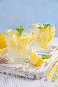 夏季柠檬果汁摄影照片_提神的夏季饮料与柠檬和薄荷木制背景上的冷.