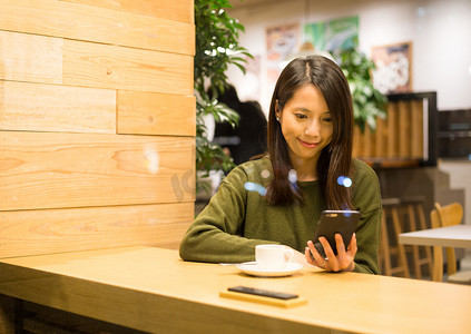 阅读坚持摄影照片_使用智能手机，在咖啡厅里的女人