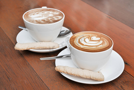 两杯的木制背景上的白色杯咖啡拿铁艺术