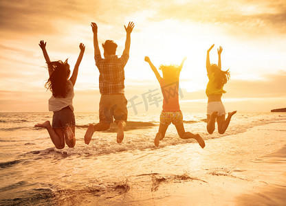 跳跃人摄影照片_一群快乐的年轻人在海滩上跳跃