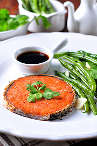 三文鱼扒摄影照片_Salmon steak with green beans, garlic, black sesame and soy sauce. Selective focus.