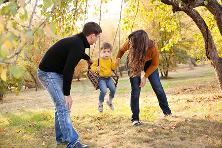 幸福的家庭乐趣摇摆骑在一个秋日的花园