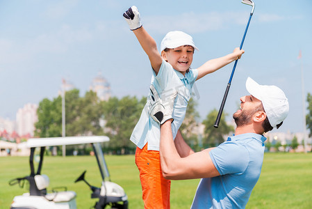 man picking up his son on golf course