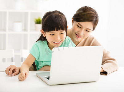 快乐的小女孩，用她的母亲看着笔记本电脑