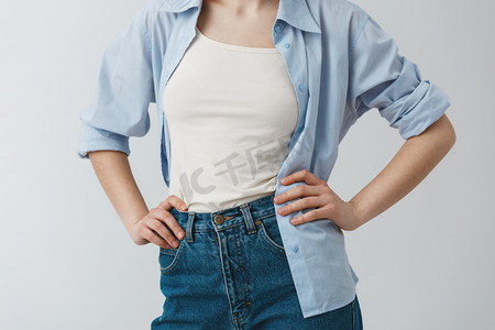 关闭年轻女学生的手在腰部的时髦衣服的细节, 穿着白色 t-shirt 在蓝色衬衣和牛仔裤之下.