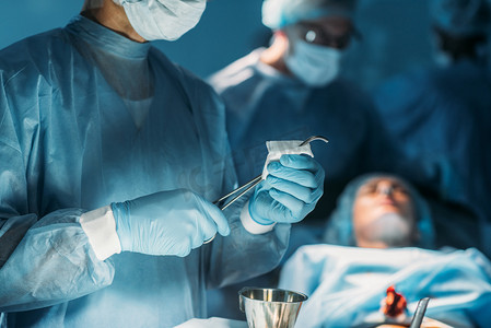 uniform摄影照片_外科医生在手术室清理手术镊子的图像