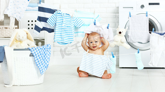 有趣的开心宝贝男孩洗衣服和发笑，但在洗衣