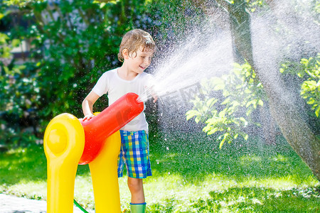 小家伙玩花园水管喷水的男孩