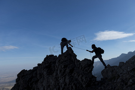 登山团队摄影照片_在山上的岩石上的团队精神