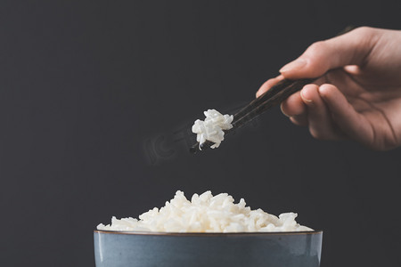 好味道摄影照片_妇女用筷子从碗里拿刚熟的米饭