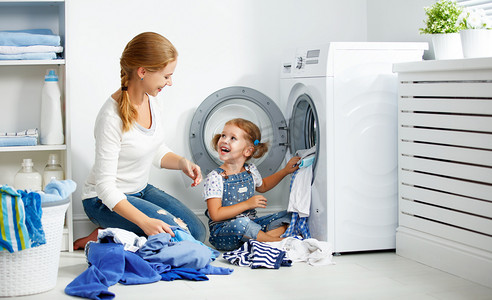 热点摄影照片_家庭的母亲和儿童女孩在洗衣房附近洗机