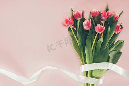 国际幸福日摄影照片_粉红色的绿叶和丝带美丽的粉红色郁金香花束 