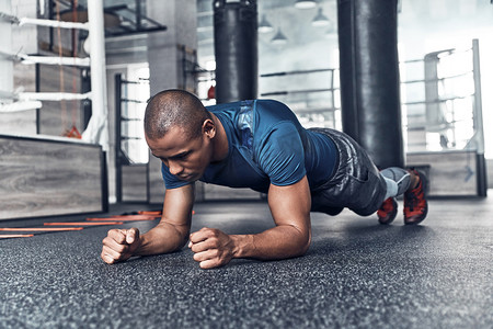 肌肉发达的年轻非洲男人在健身房做木板运动